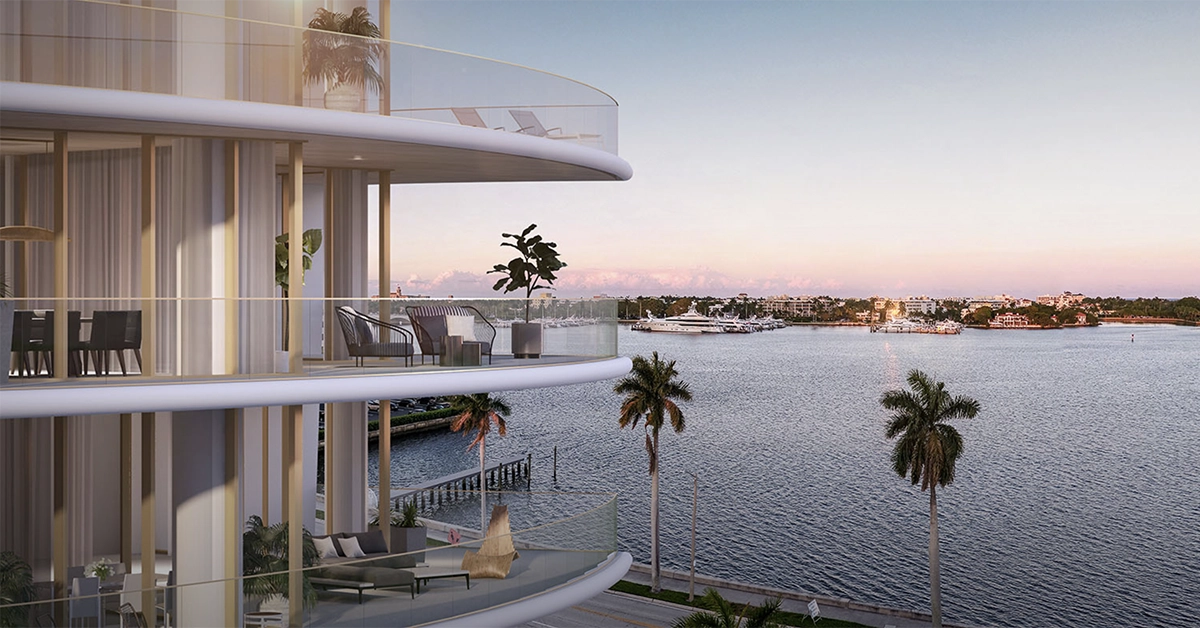 Expansive balcony view overlooking calm waterfront and palm trees at sunset from a luxury residence.